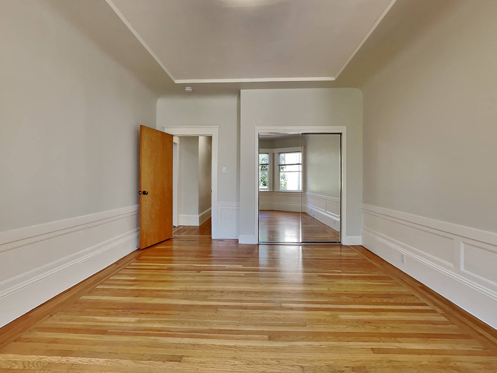 a living room with white walls and a wooden floor    and a door