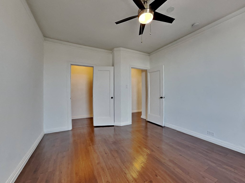 an empty living room with white walls and a ceiling fan