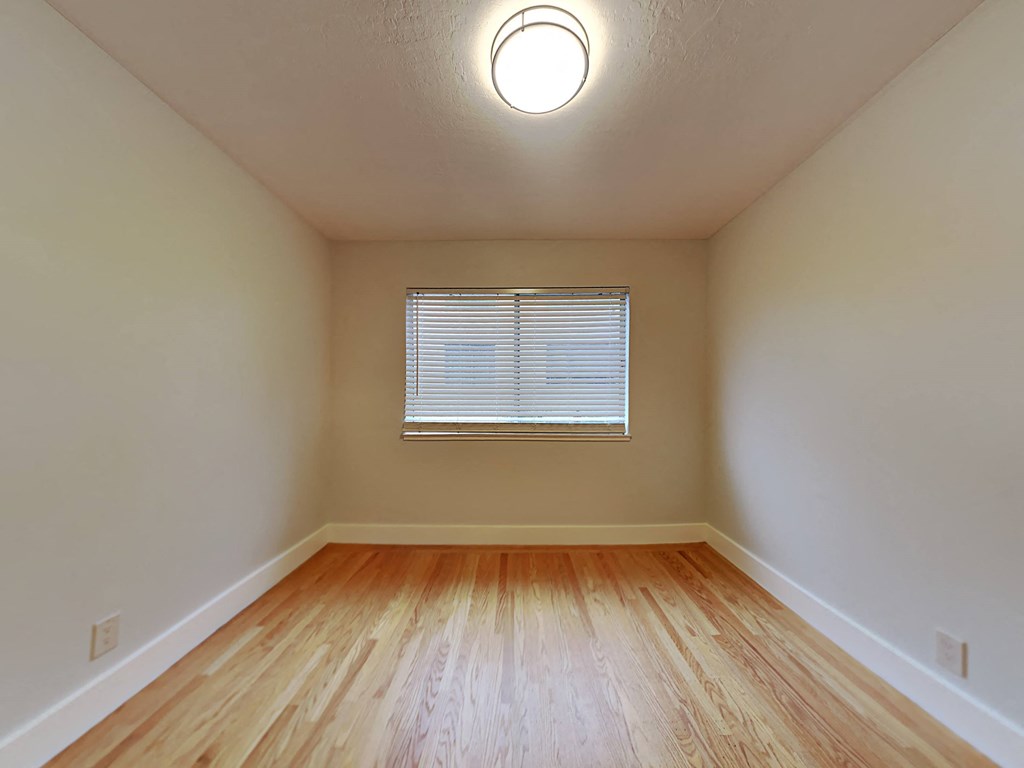 an empty room with wood floors and a window