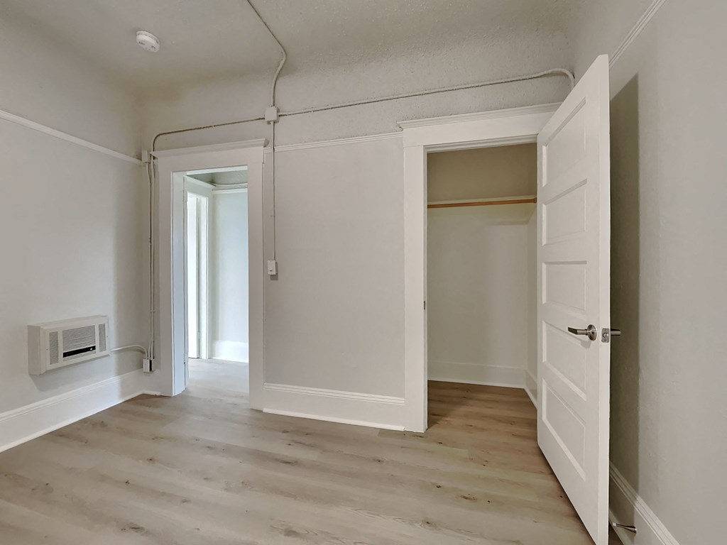 an empty room with a white door and a hallway with a closet