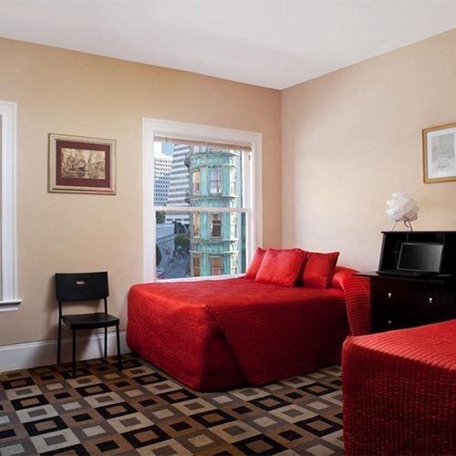 a bedroom with a red bed and a window