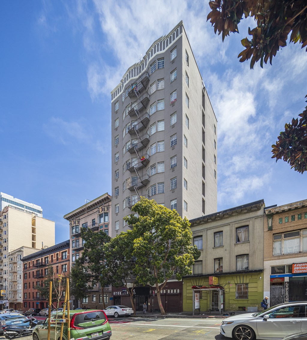 a tall white building with balconies on a city street