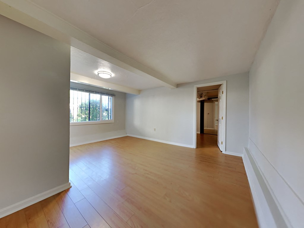 an empty living room with wood floors and white walls