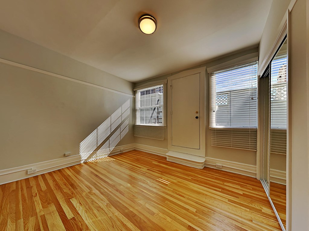 an empty living room with wood flooring and a window