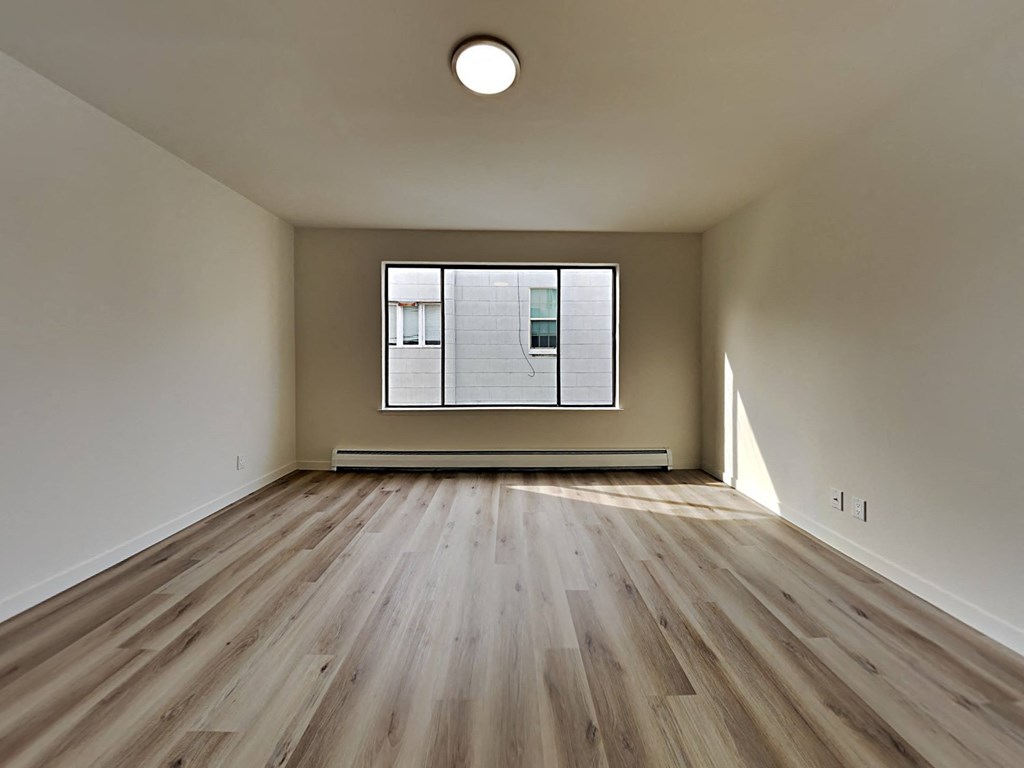 an empty living room with wood floors and a window