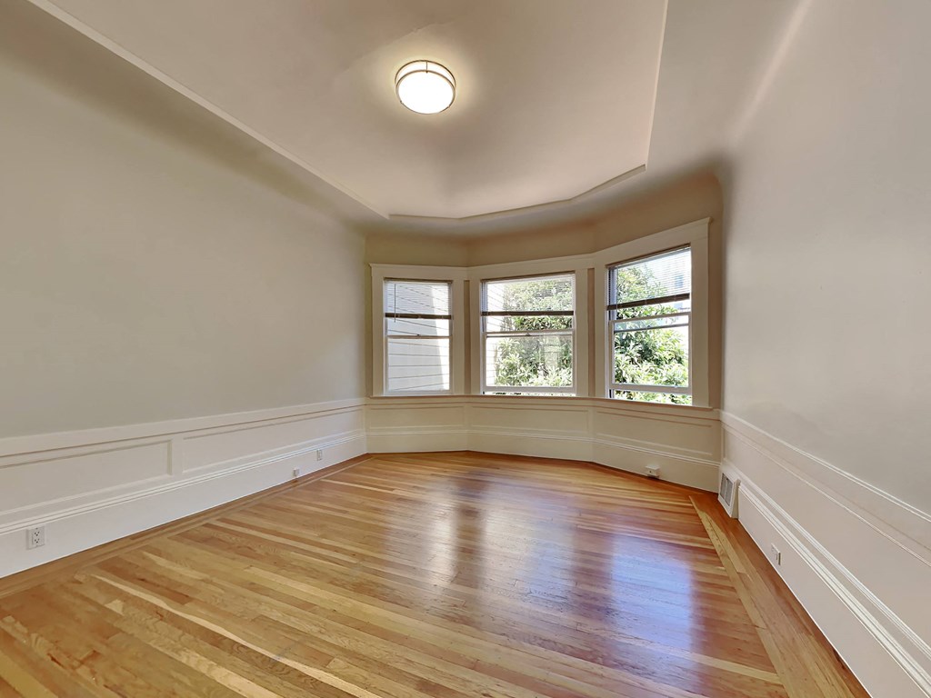 an empty living room with hardwood floors and a bay window