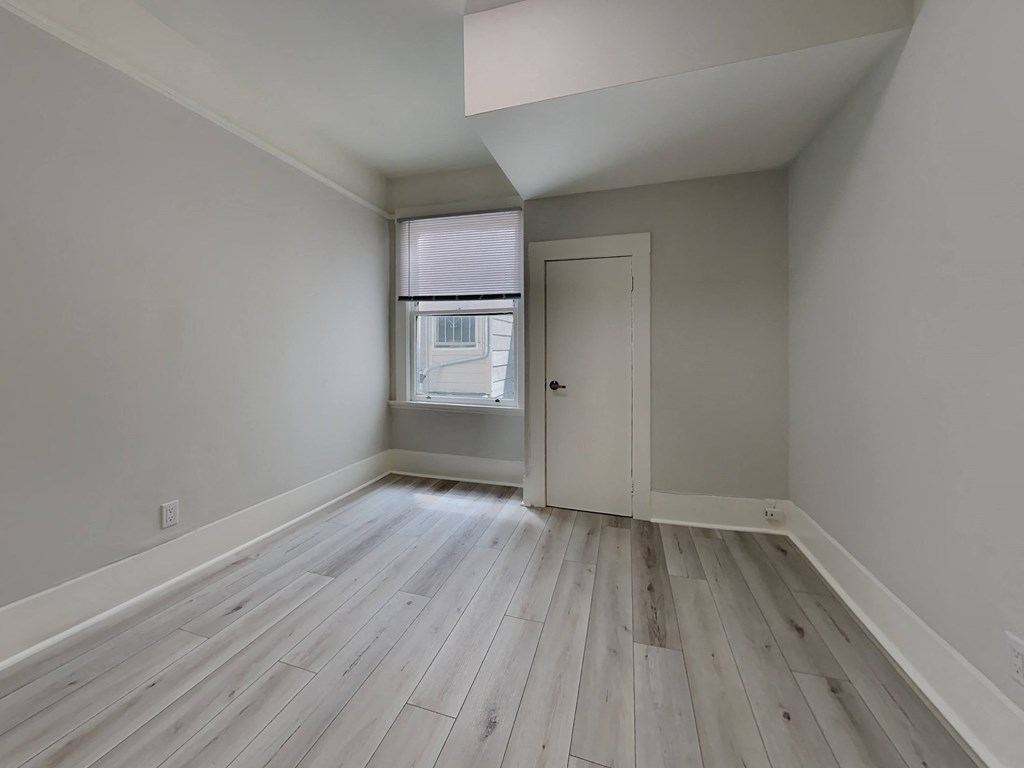 an empty room with wood floors and a window