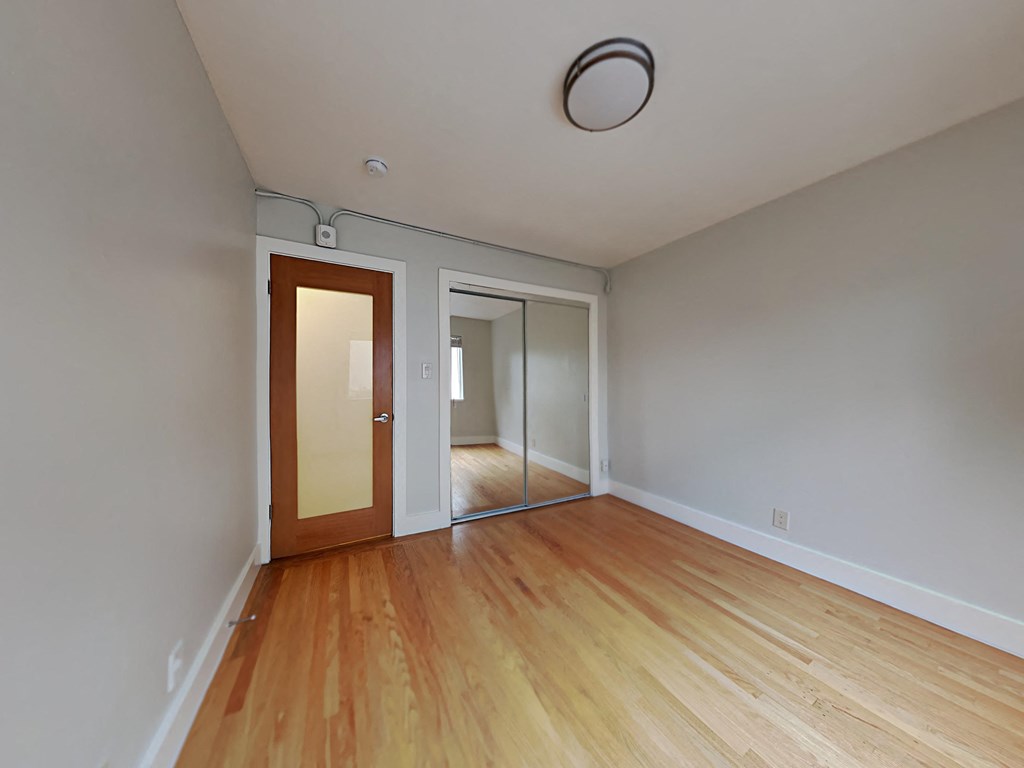 a living room with wood floors and a door to a hallway