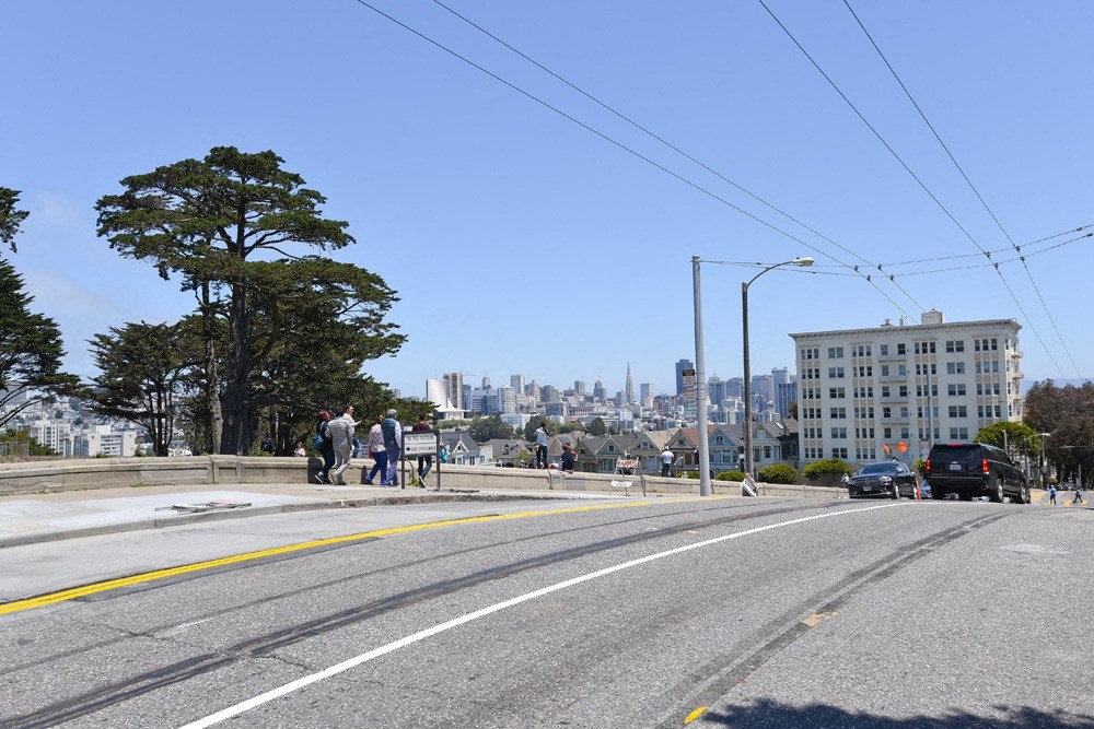 people are standing on a bridge over a street with a city in the background