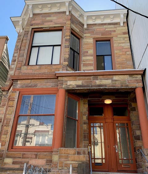the front of a brick building with orange doors and windows
