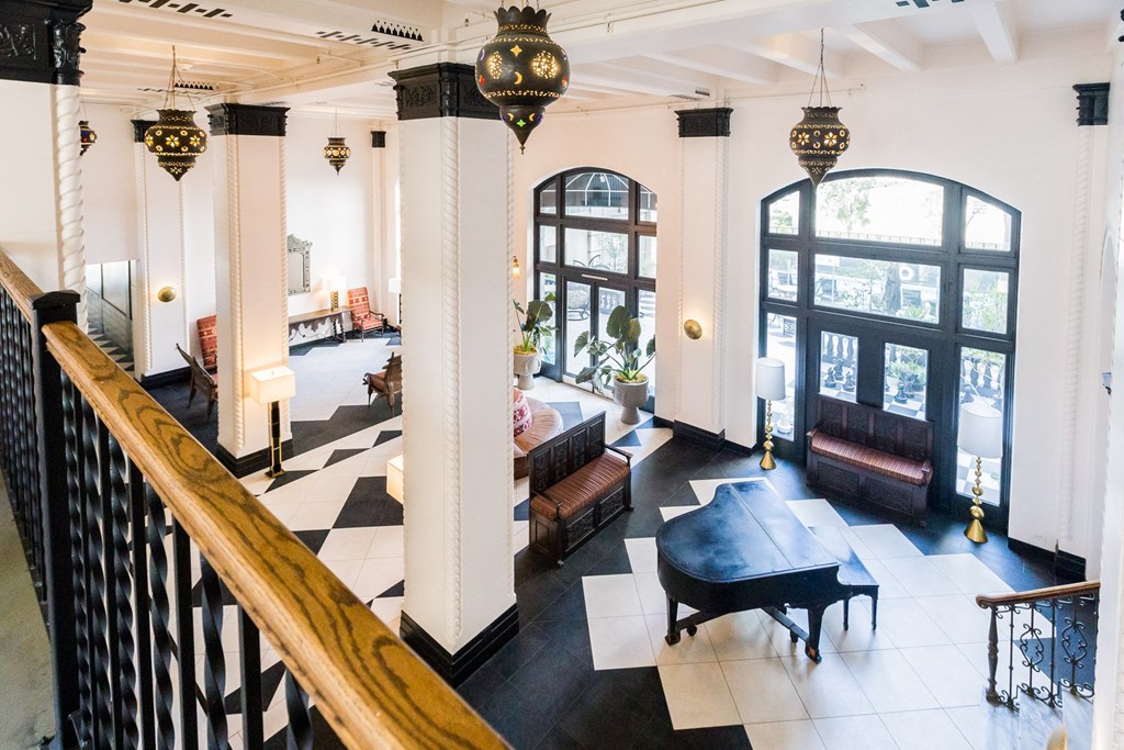 the lobby of a hotel with a piano and a staircase
