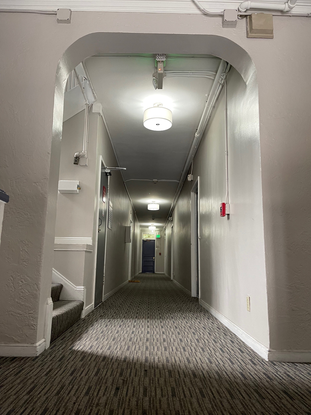 a hallway with a carpeted floor and a door at the end of a room