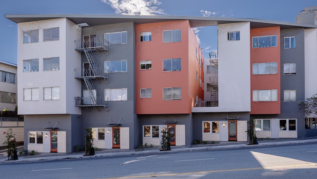 a street view of an apartment building with balconies and a road
