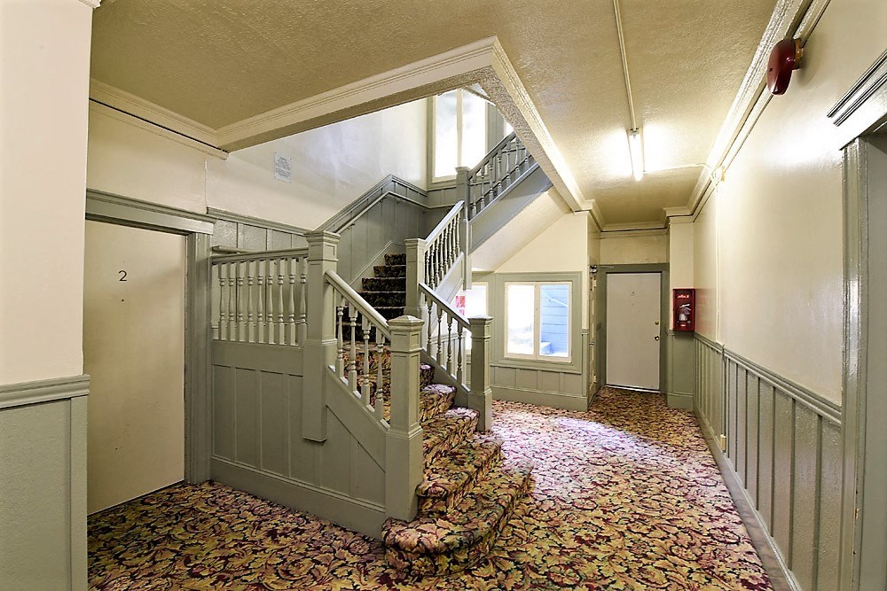 the lobby of a building with stairs and a hallway with a carpeted floor