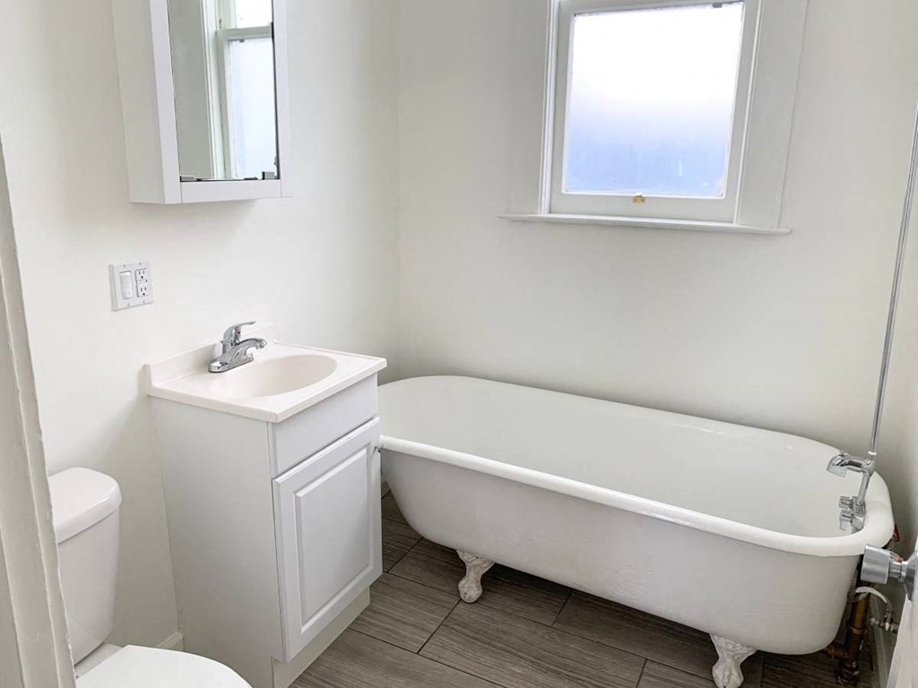 a bathroom with a bath tub and a sink and a window
