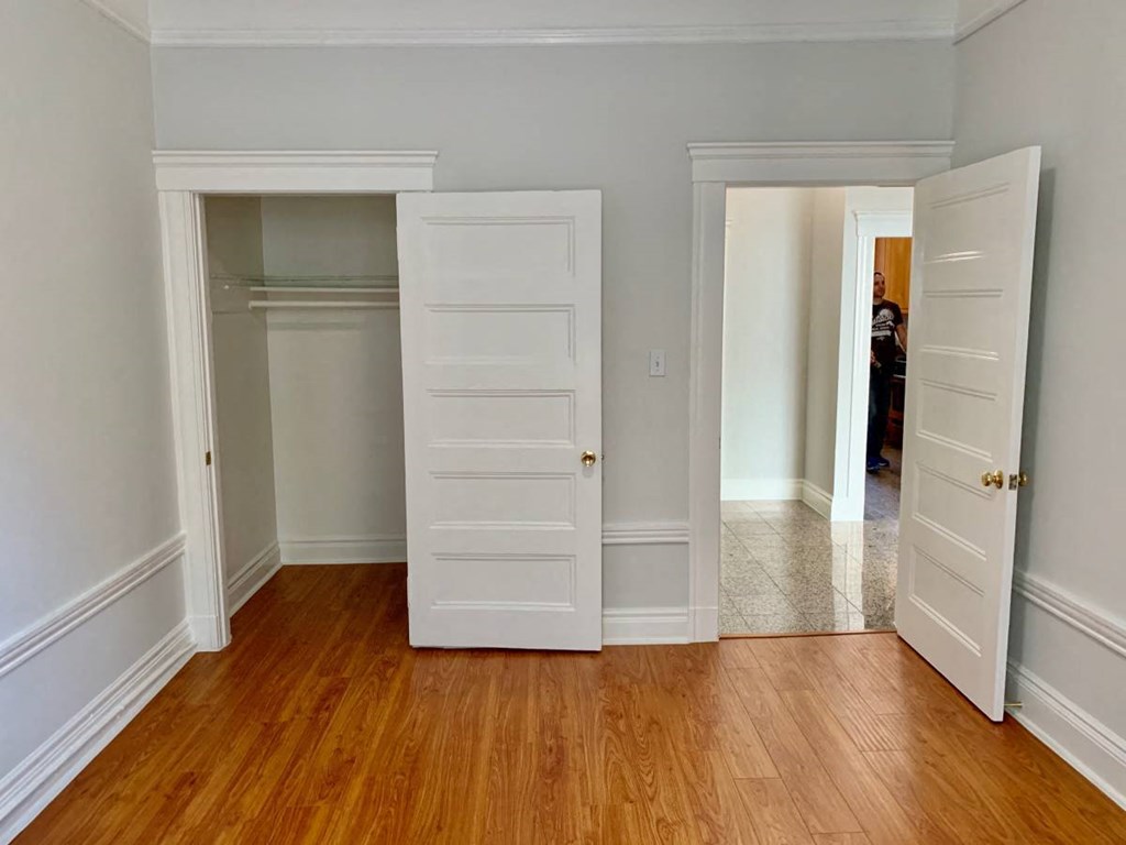 an empty room with white doors and a wood floor