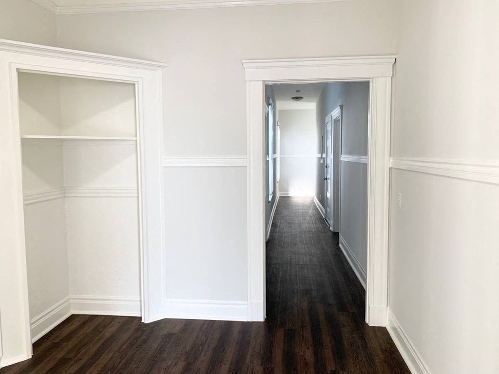 a bedroom with a hallway with white walls and a closet