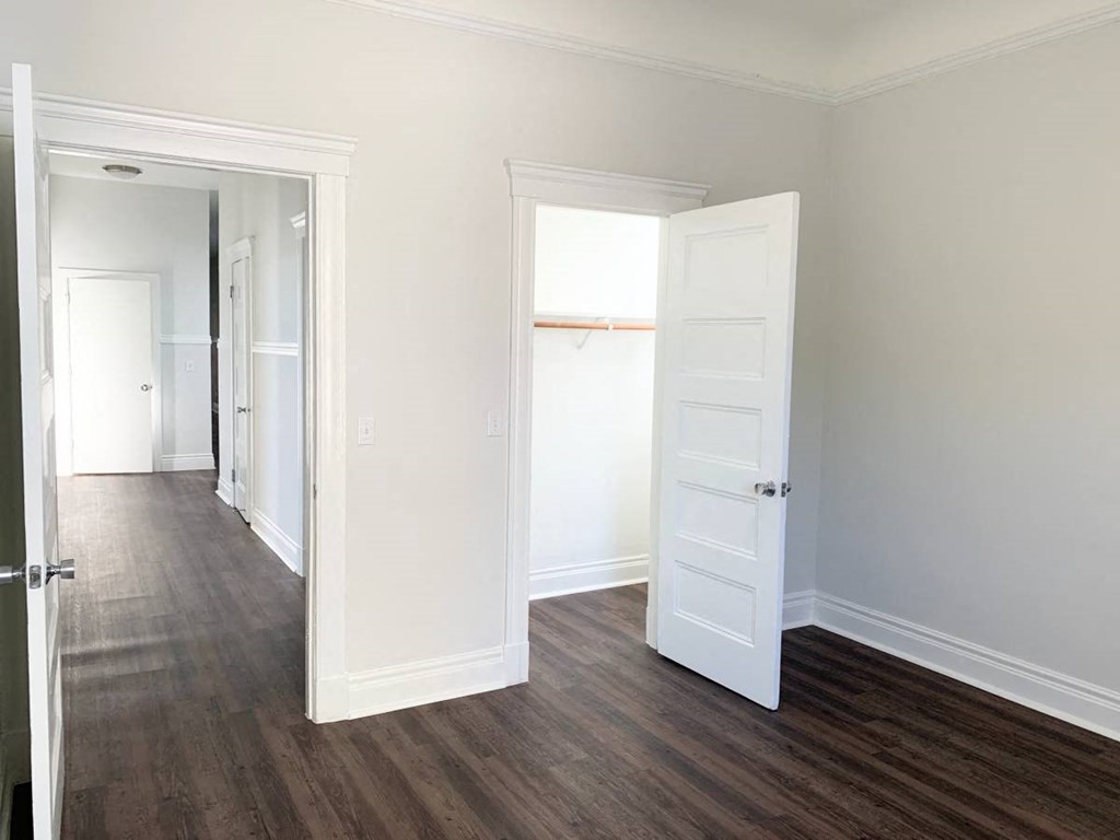 a bedroom with an open door and a hallway with a door to a closet