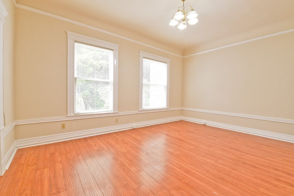 an empty living room with wood floors and three windows