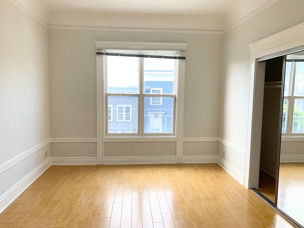 an empty living room with two windows and a wooden floor
