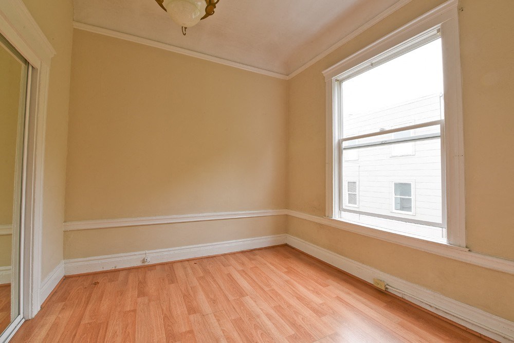 an empty room with wooden floors and a window
