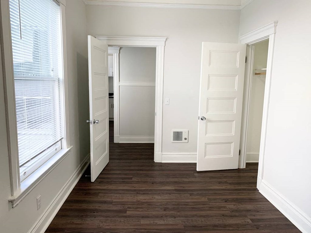 a bedroom with a hard wood floor and a door to a closet