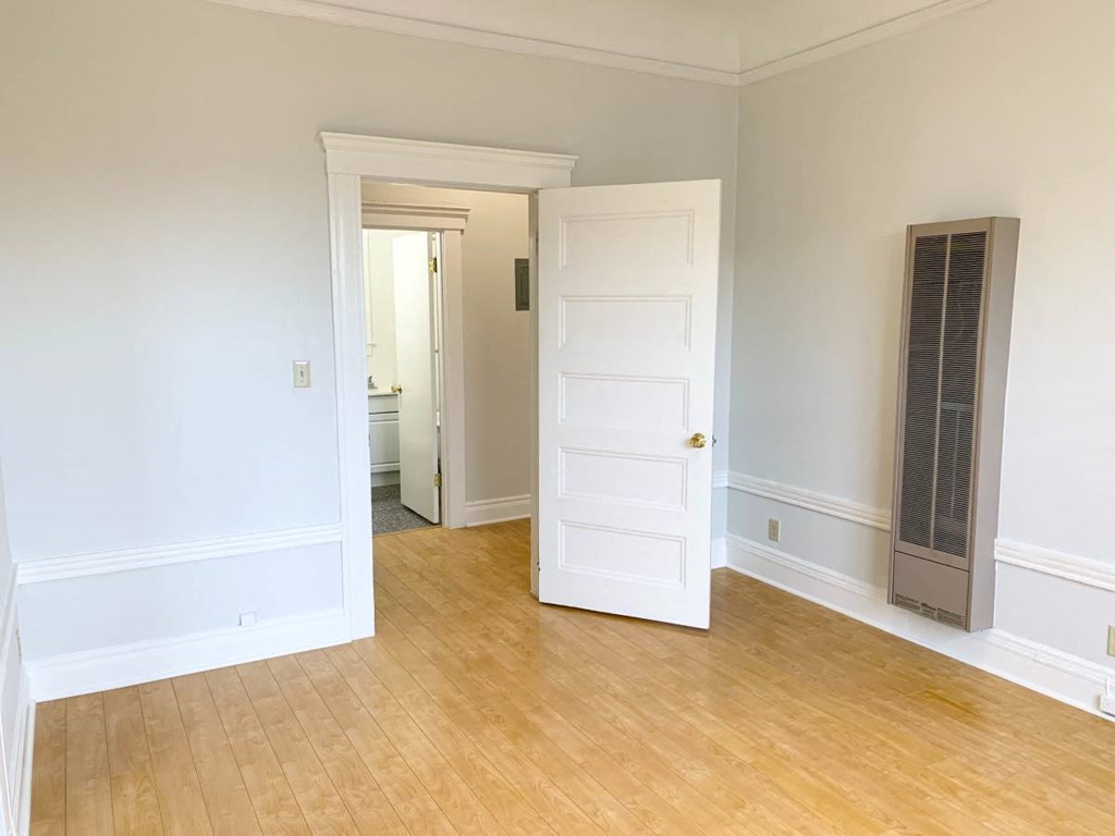 an empty living room with a white door and a wood floor
