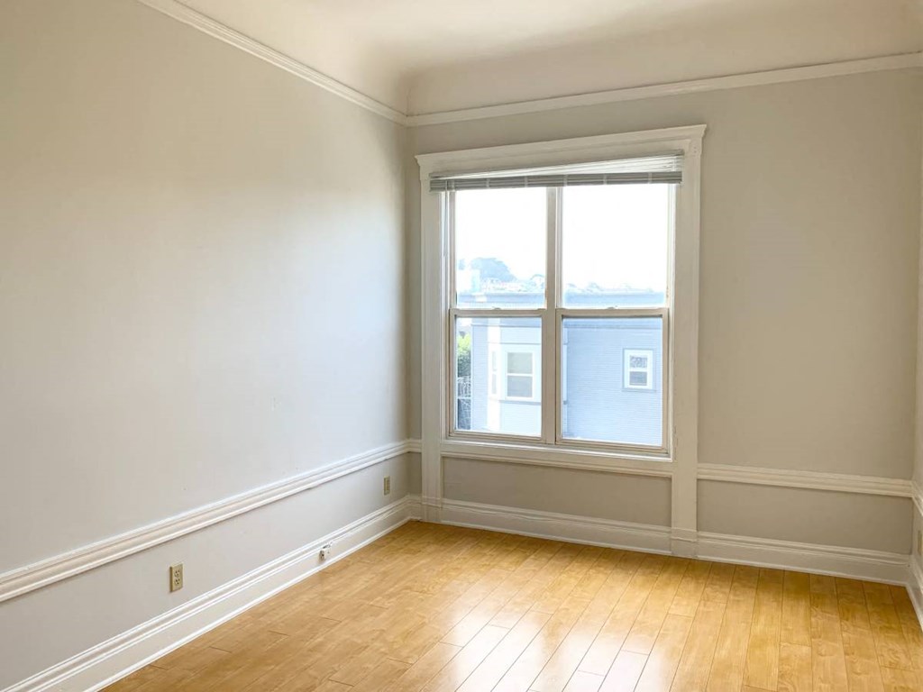 an empty room with a window and wooden floors