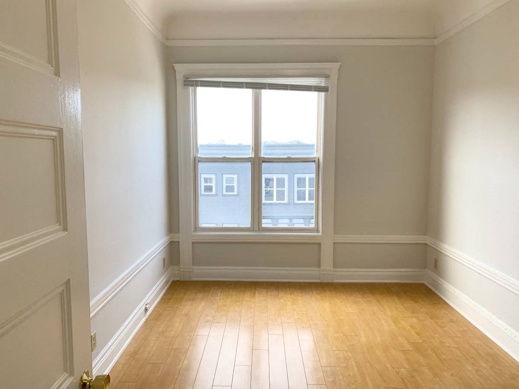 an empty room with a window and wooden floors