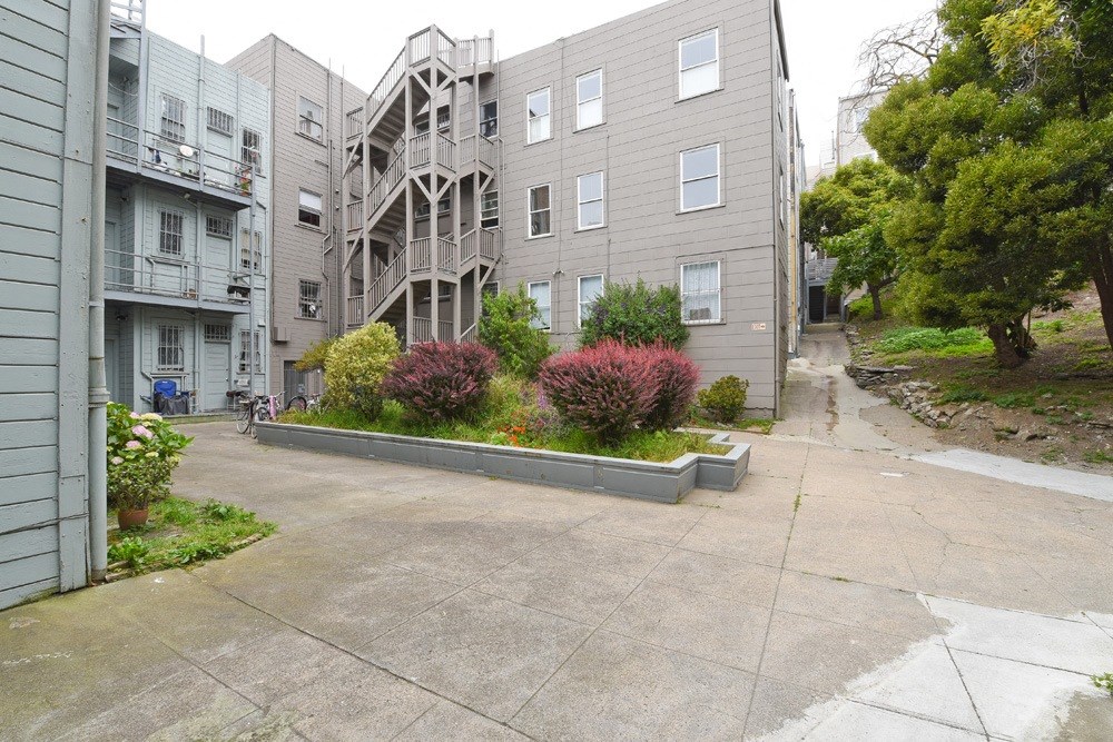 the view of an apartment building with a driveway and landscaping in front of it
