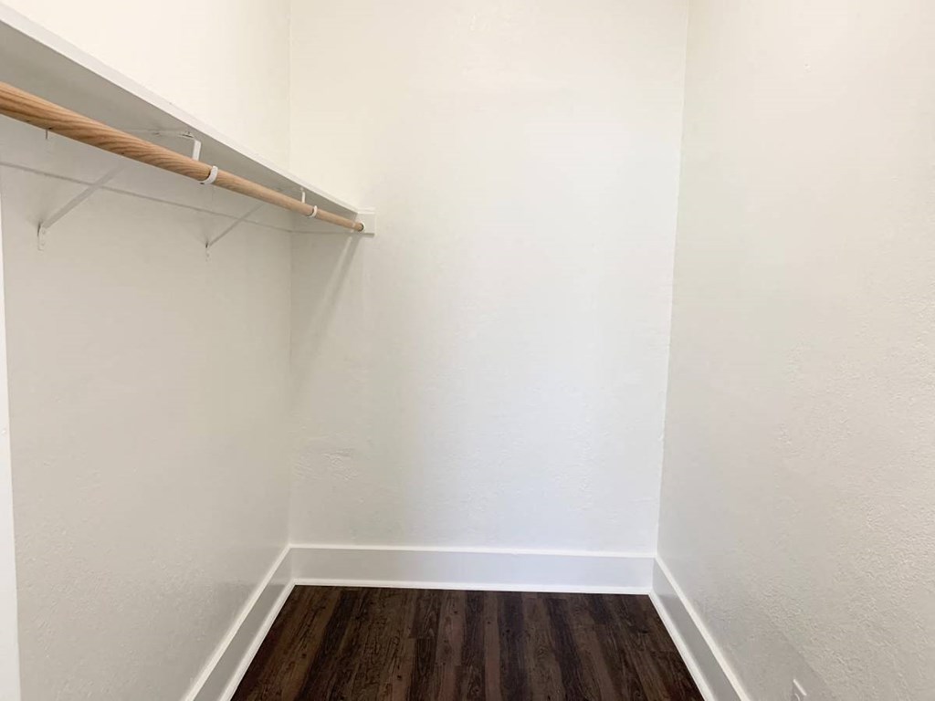 a closet in a small room with white walls and a wooden floor