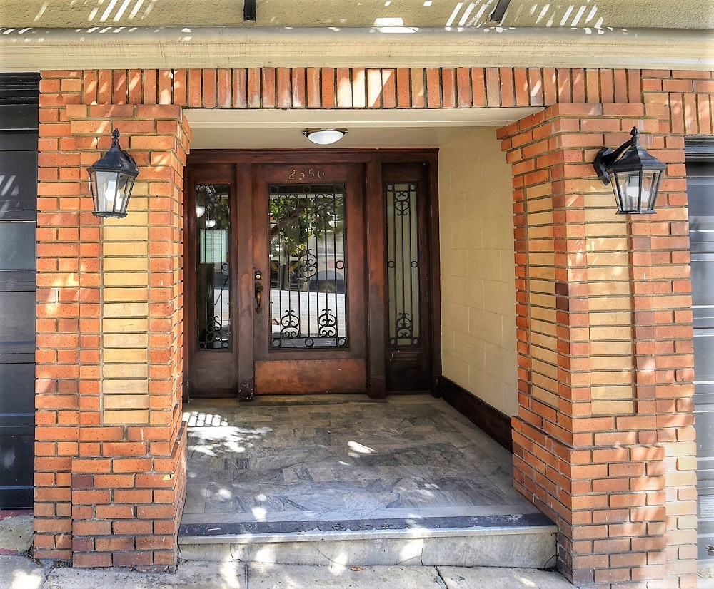 the front door of a building with two lanterns on the side