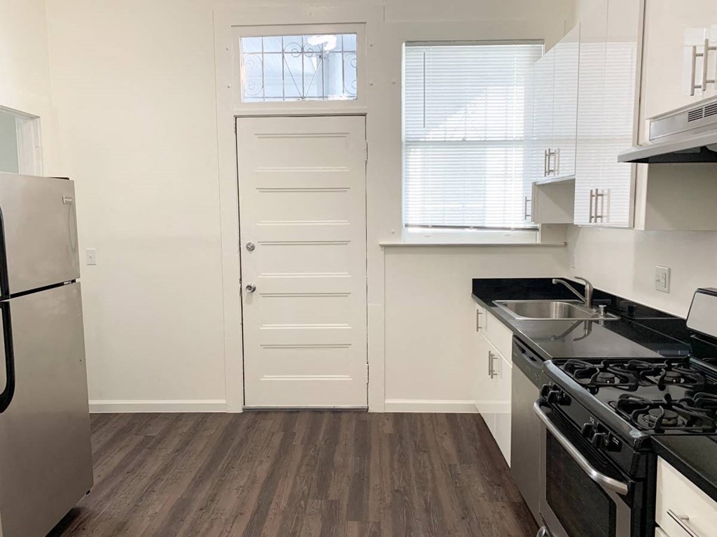 a kitchen with a stove and a sink and a door