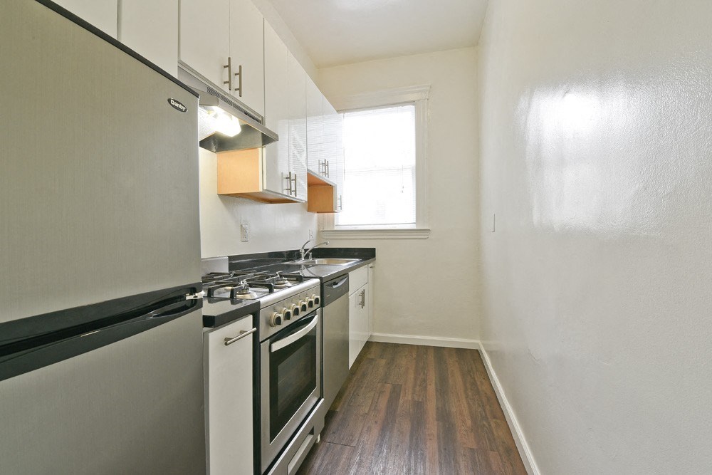 an empty kitchen with stainless steel appliances and white cabinets