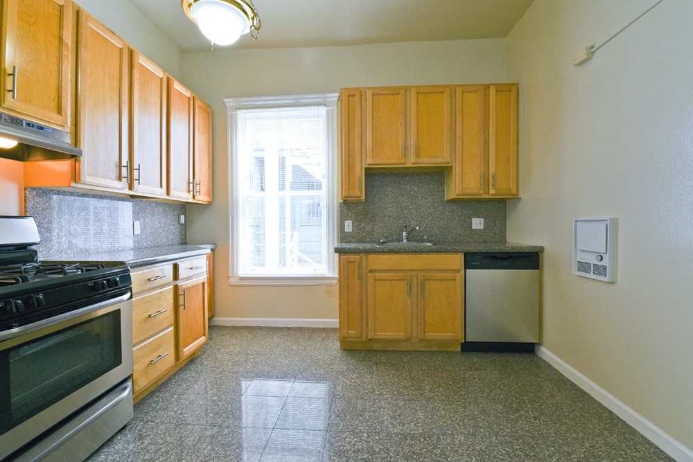 an empty kitchen with wooden cabinets and a window