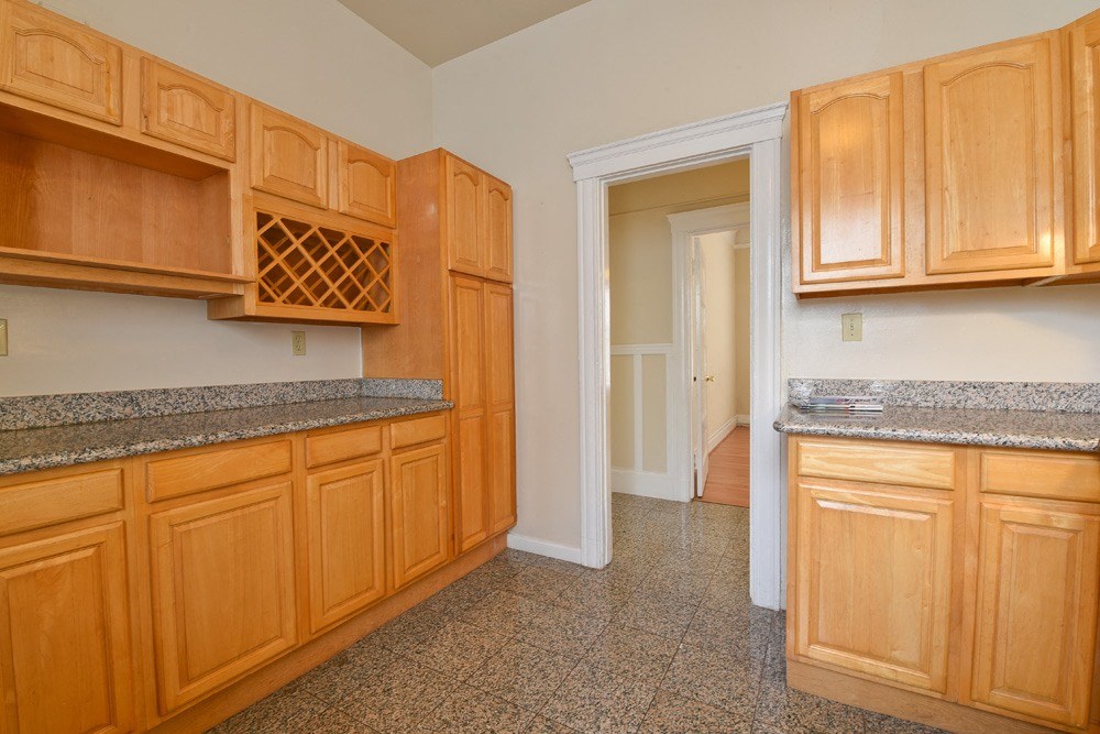 a kitchen with wood cabinets and granite counter tops and a door to a hallway