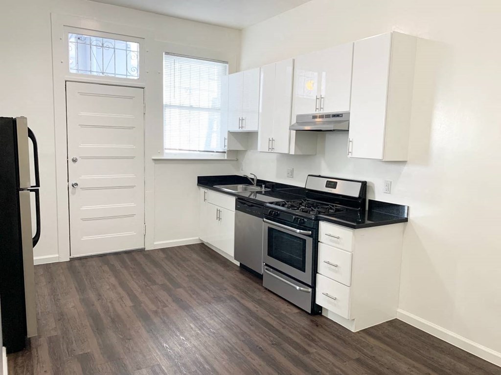 an empty kitchen with white cabinets and a stove