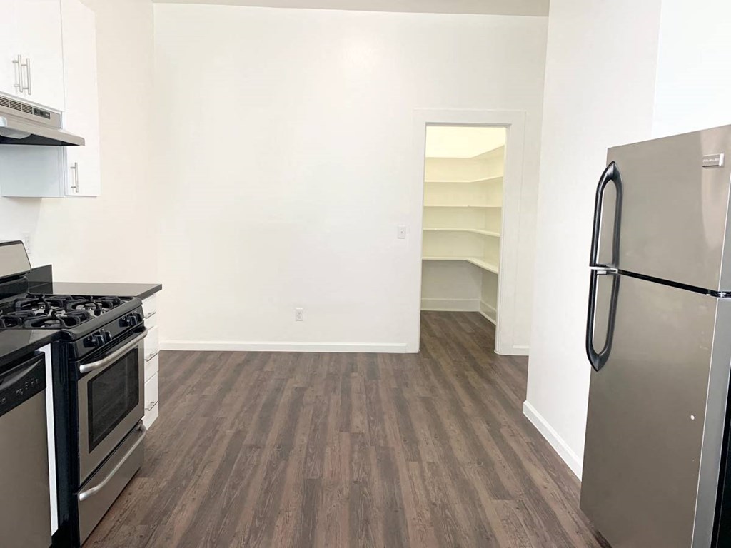 a kitchen with a stove and a refrigerator in a room