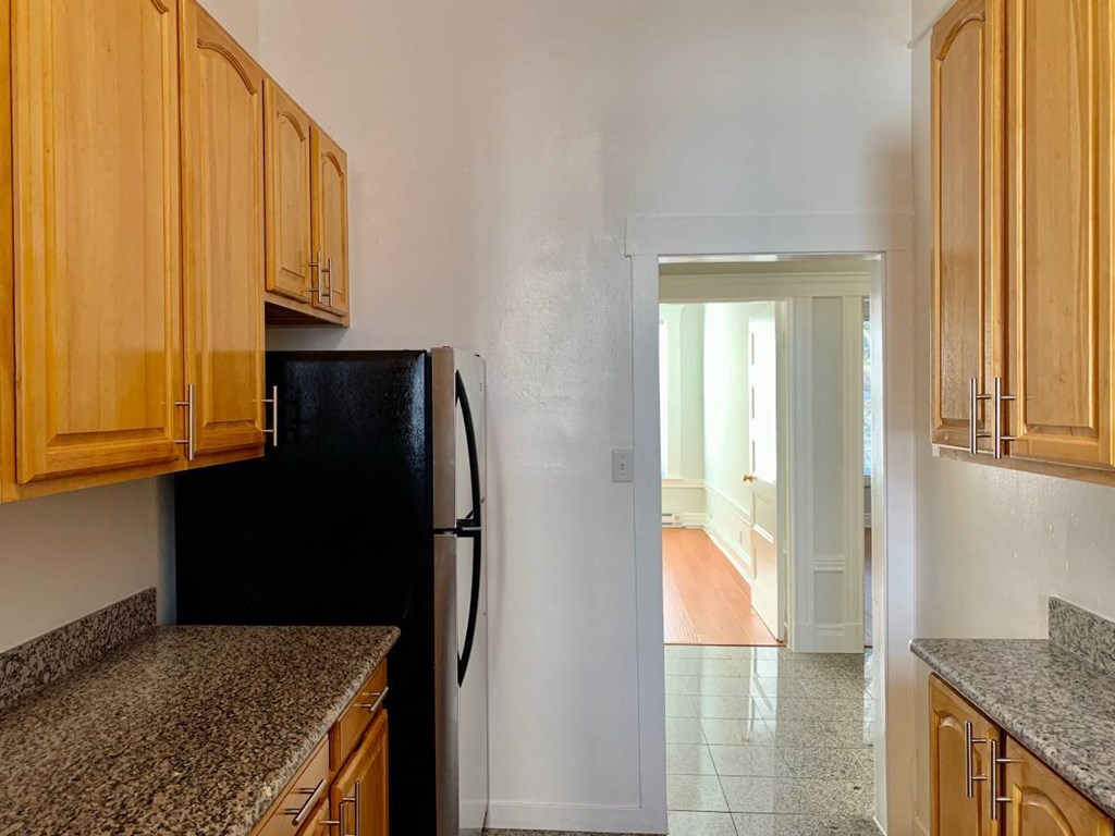 a kitchen with a black refrigerator and wooden cabinets