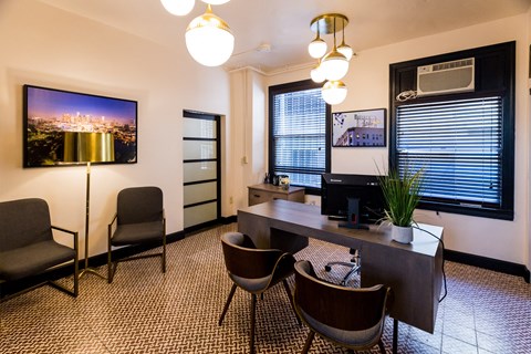 a conference room with a desk and chairs and a tv