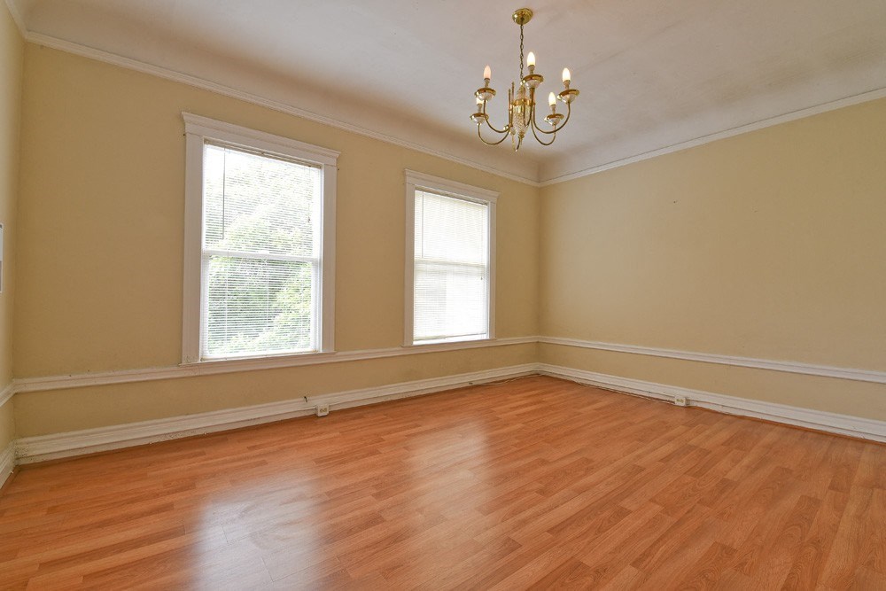 an empty living room with wooden floors and three windows