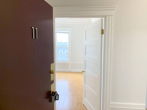 the door is open to a empty room with a window