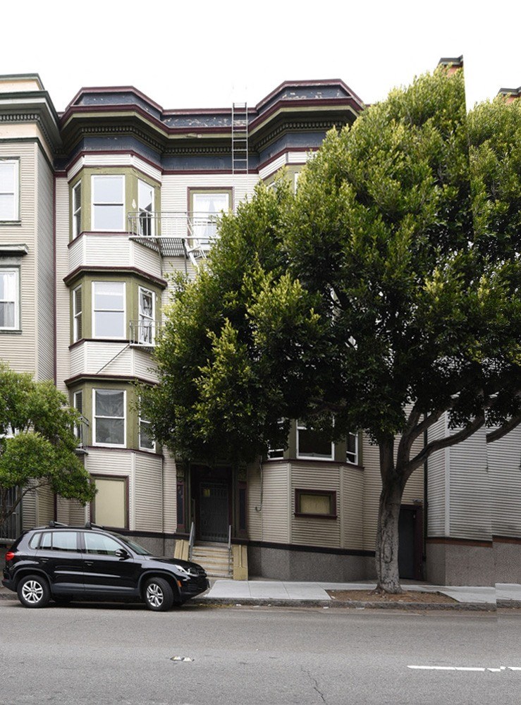 a car parked in front of a tall apartment building