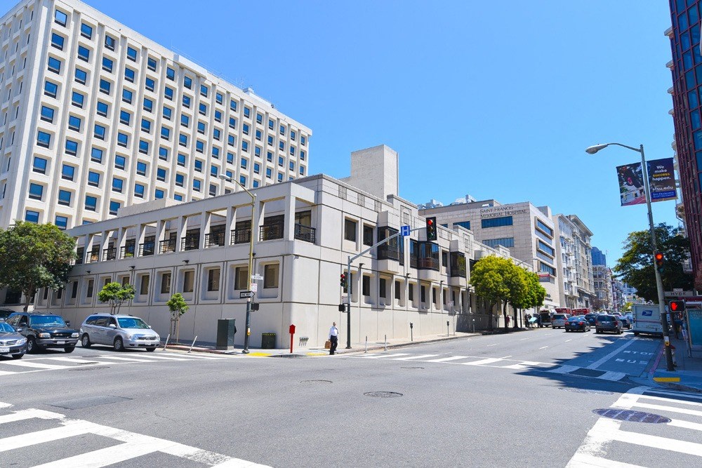 a city street with a large white building on the corner