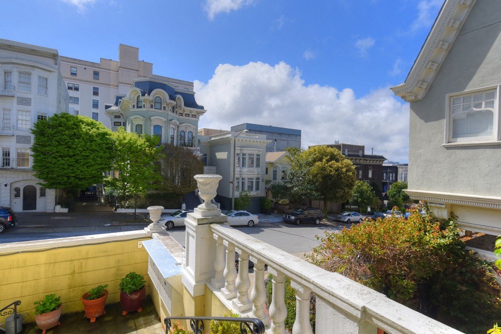 a view of a city street from the balcony of a house