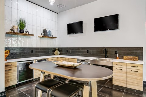 an entertainment kitchen with a table and chairs in front of a sink located in the community clubroom