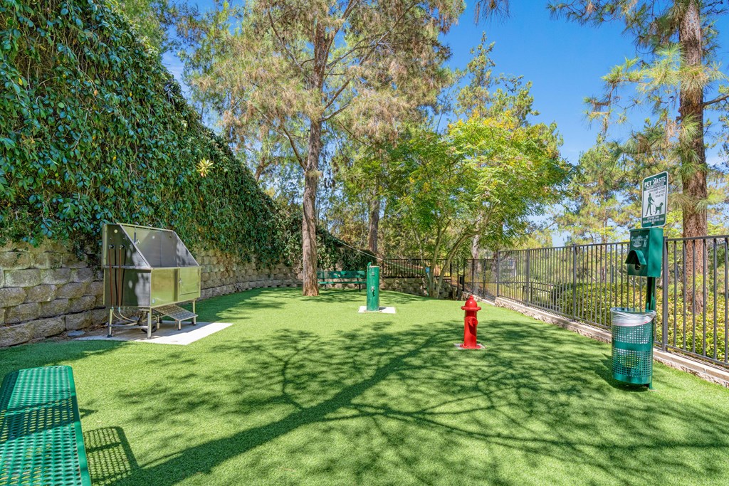 A green lawn with a red fire hydrant and a green trash can.