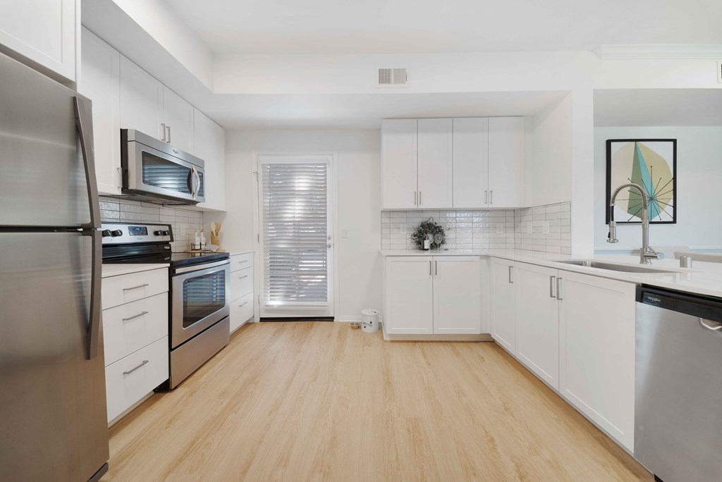 A kitchen with white cabinets and a wooden floor.