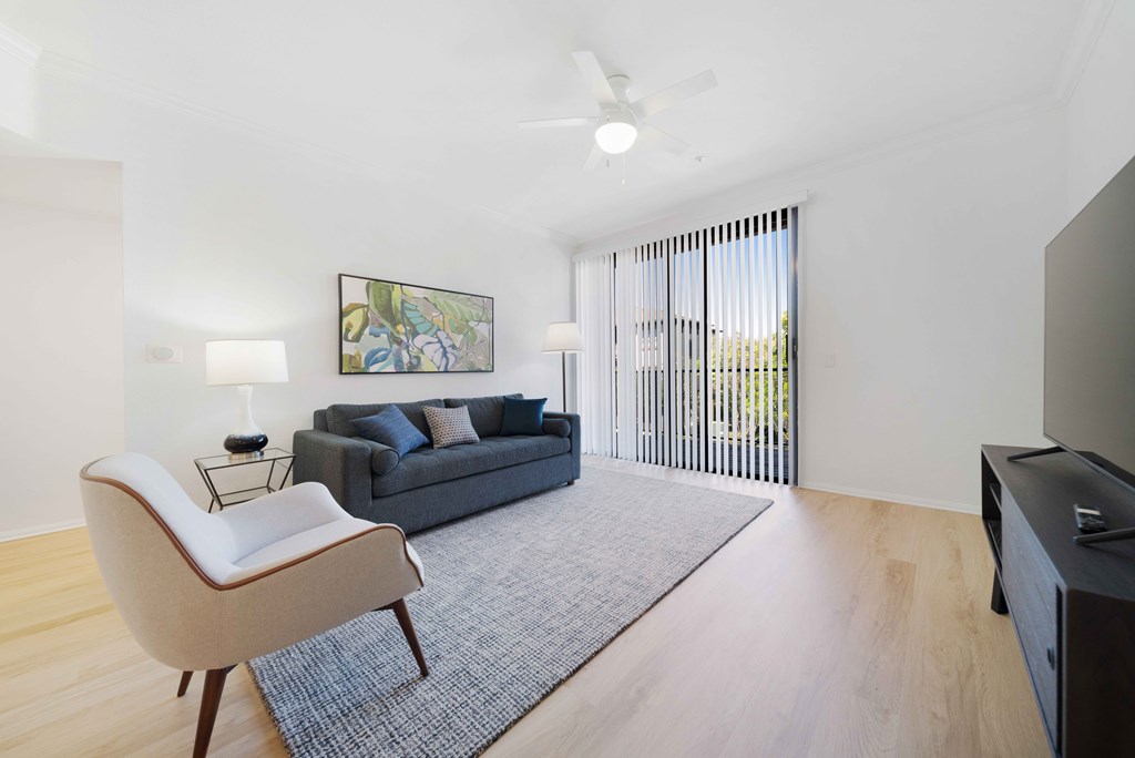 A living room with a grey couch, a white chair, and a painting on the wall.