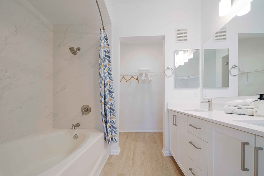 A white bathroom with a tub, sink, and mirror.